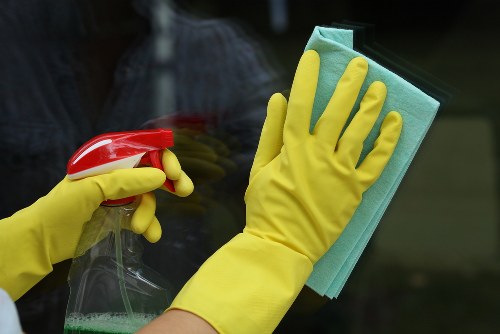 Professional cleaner washing exterior windows on a bright building